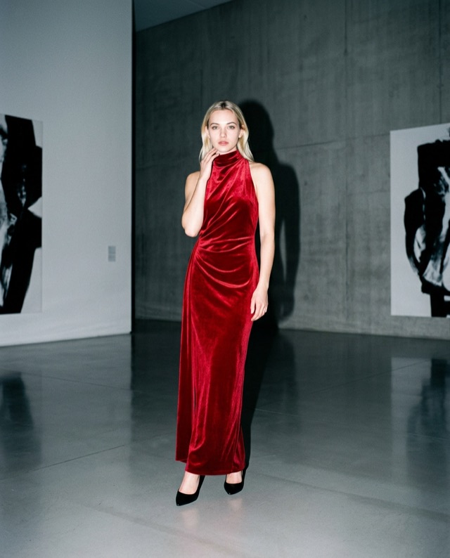 Alina in a red evening dress among artworks in a gallery.